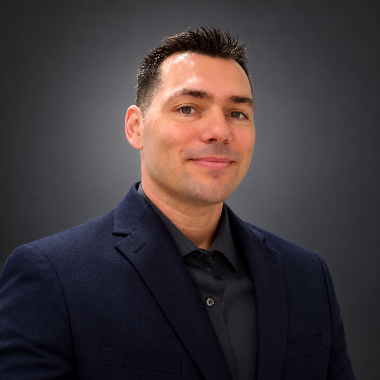 Ervin Hodzic in a navy jacket against a charcoal studio background